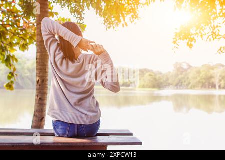 Soft Light and Blur, Eine junge Frau sitzt abends allein auf einer Holzbank am Wasserturm. Eine Frau, die gestresst und depressiv war, saß Stockfoto