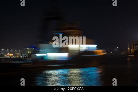 Ein Seetschlepper, der in den Hafengewässern segelt. Nachtfoto mit langer Belichtungszeit und verschwommener Bewegung. Swinoujscie, Polen, Polska. Stockfoto