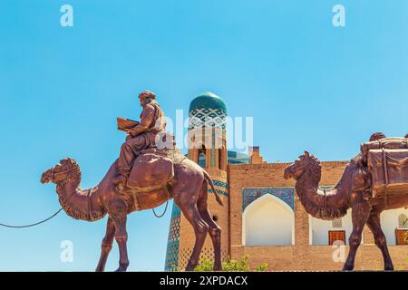 Skulpturengruppe einer Karawane mit Kamelen, die Güter entlang der Seidenstraße in der Nähe der alten Stadtmauern transportieren. Chiwa, Usbekistan - 17. Juli 2024. Stockfoto