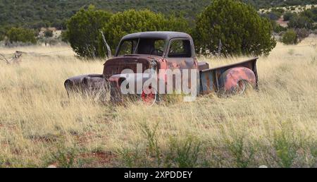 Ein Lone Truck sitzt verlassen und verrostet, auf einem Feld auf einer Hinterstraße in New Mexico. Er ist mit Rost bedeckt, aber ein wenig roter Überreste des ursprünglichen Lkws Stockfoto