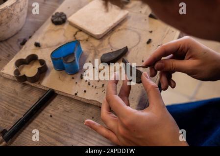 Weibliche Hände schnitzen einen Topf in Ton während eines Töpferkurses Stockfoto