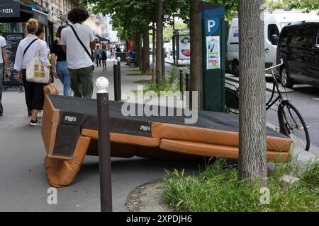 Paris, Frankreich - 07. Juni 2024: Ledersofa auf der Straße entsorgt. Leute, die auf dem Bürgersteig vorbeigehen Stockfoto