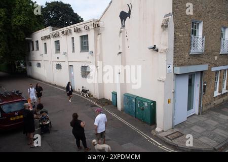 London, Großbritannien. August 2024. Die Leute fotografieren das neueste Kunstwerk des Street Artist Banksy, das eine Bergziege zeigt, die auf der Säule eines Gebäudes thront und Felsen an der Kew Bridge herunterfallen. Quelle: Justin Ng/Alamy Live News. Stockfoto