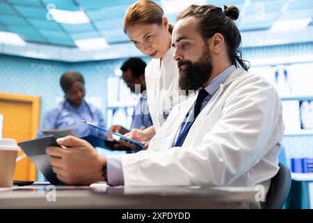 Ärzteteam, das in einem medizinischen Behandlungszentrum arbeitet, um die Diagnose zu finden. Professionelle Experten engagierten sich in einem Meeting über Prüfungsergebnisse in einer privaten Klinik, Healthcare Industrie Teamwork. Stockfoto