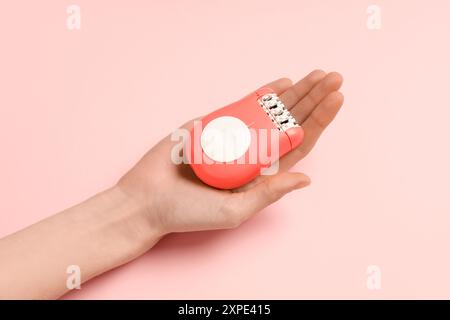 Weibliche Hand mit modernem Epilierer auf rosafarbenem Hintergrund Stockfoto