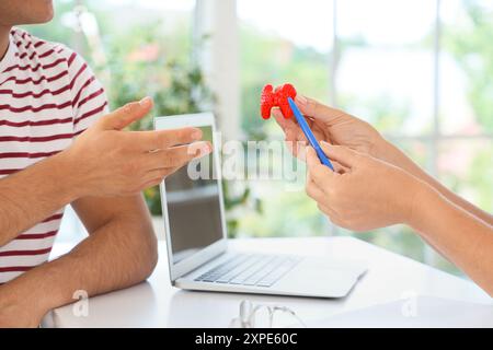 Endokrinologin zeigt Schilddrüsenmodell dem Mann in der Klinik, Nahaufnahme Stockfoto