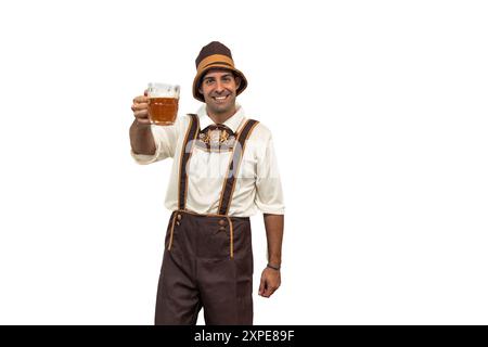 Junger bayerischer Mann in traditioneller Kleidung, der während des Oktoberfestes mit einem Glas Bier auf dem weißen Hintergrund auf die Kamera tobt Stockfoto