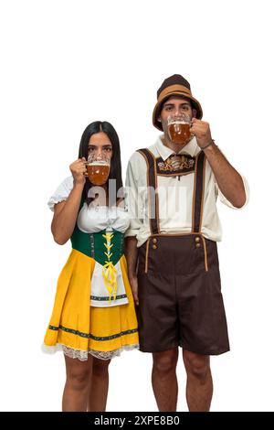 Vertikales junges bayerisches Paar in traditioneller Oktoberfestkleidung, das Bier trinkt. Das Bild fängt die festliche Atmosphäre und den kulturellen Tradi ein Stockfoto