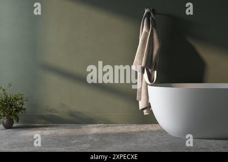 Eine weiße Badewanne befindet sich vor einer grünen Wand. Ein Handtuch hängt an einem Haken über der Wanne Stockfoto