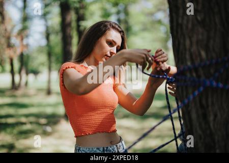 Eine junge Frau, die an einem sonnigen Tag im Park eine Hängematte aufstellt Stockfoto
