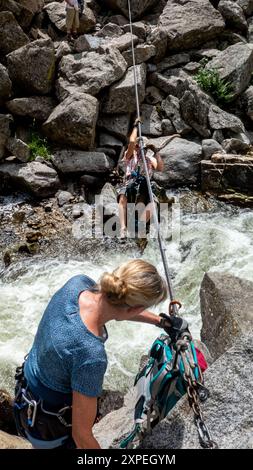 Zwei erwachsene Frauen überqueren eine tiroler Überquerung oberhalb des Boulder Creek im Boulder Canyon, Boulder, Colorado Stockfoto