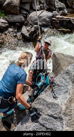 Zwei erwachsene Frauen überqueren eine tiroler Überquerung oberhalb des Boulder Creek im Boulder Canyon, Boulder, Colorado Stockfoto