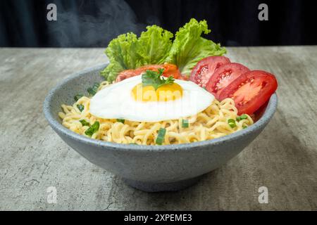 Eine Schüssel mit Instantnudeln mit Eiern, Tomaten und Salat Stockfoto