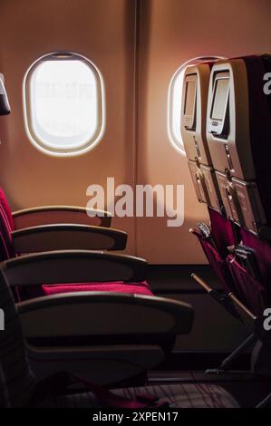 Leere Sitze in einer Flugzeugkabine neben den Fenstern. Stockfoto