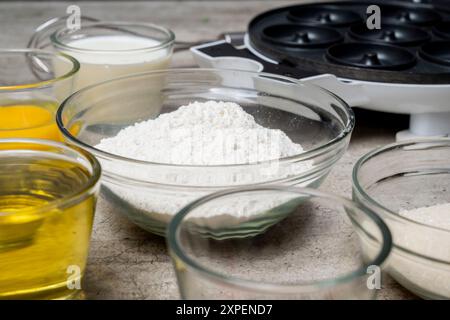 Ein Tisch mit mehreren Schüsseln mit Zutaten, einschließlich Mehl, Zucker und Öl. Die Schüsseln sind in einer Reihe angeordnet, wobei einige Schüsseln trockene Zutaten enthalten Stockfoto
