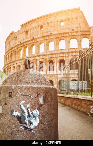 Rom, Italien, 20. Februar 2020. Das Kolosseum erhebt sich majestätisch im Hintergrund, mit Graffiti eines herabfallenden Engels mit Pfeilen im Vordergrund Stockfoto