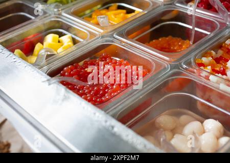 Ein Blick auf mehrere Behälter voller Beläge in einem gefrorenen Joghurt oder einer Eisdiele. Stockfoto