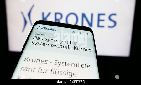 Mobiltelefon mit Website des deutschen Maschinenbauunternehmens Krones AG vor dem Firmenlogo. Fokussieren Sie sich oben links auf der Telefonanzeige. Stockfoto