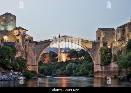 Mostar, Bosnien und Herzegowina - August 2023: Alte Brücke ('Stari Most') und Koski Mehmed Pascha Moschee ('Koski Mehmed-pašina džamija') beleuchtet nach Stockfoto