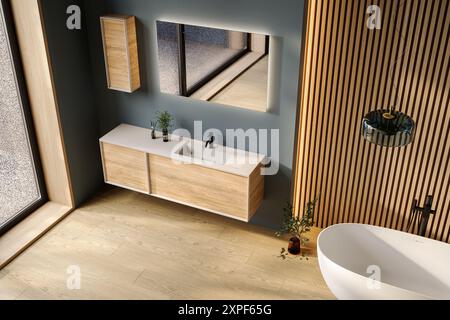 Komfortable Badewanne und Kosmetikbereich mit Waschbecken im modernen Badezimmer mit blauen und hölzernen Wänden und Holzboden. Draufsicht. Stockfoto