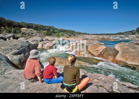 Vater und Kinder sehen Stromschnellen am Pedernales River, Pedernales Falls State Park, Hill Country, Texas, USA Stockfoto
