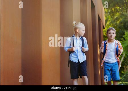 Kinder gehen an sonnigen Tagen mit Rucksäcken zur Schule. Beginn des akademischen Jahres. Bild mit selektivem Fokus Stockfoto