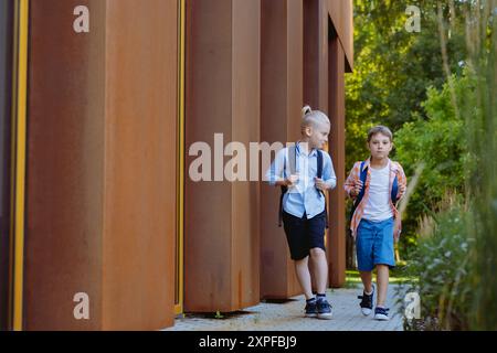 Kinder gehen an sonnigen Tagen mit Rucksäcken zur Schule. Beginn des akademischen Jahres. Bild mit selektivem Fokus Stockfoto