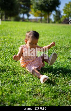 1-jähriges Latina-Baby, das auf dem Gras in einem Park sitzt Stockfoto