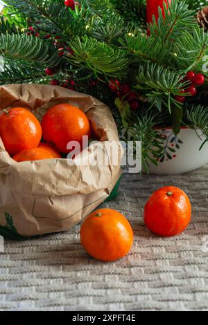 Orangenmandarinen in einem Papierbeutel in der Nähe von Fichtenzweigen. Stockfoto