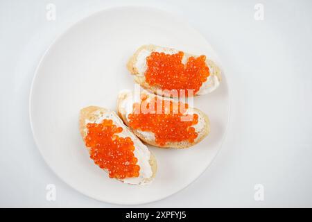 Brotscheiben mit rotem Kaviar auf weißer Platte Stockfoto