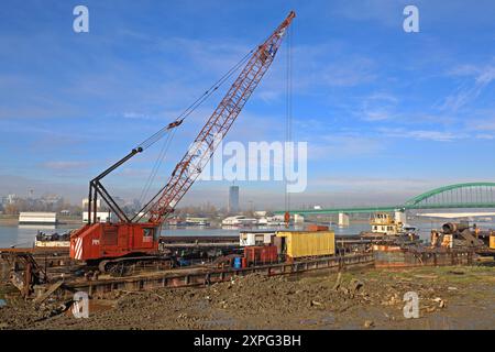 Belgrad, Serbien - 19. Dezember 2014: Raupenkran auf der alten Barge gestapelt in River Mud Construction Site. Stockfoto