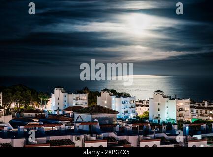 Mondlicht, Gebäude und Meer bei Nacht. Mondlicht in der Ferienstadt Benalmadena in Spanien. Ferienwohnungen und Häuser im Wohngebiet der Stadt. Stockfoto