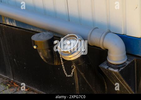 Neben einem Gebäude befindet sich ein Hydrantenanschluss, der seinen Nutzen und seine Präsenz in einer städtischen Umgebung verdeutlicht. Stockfoto