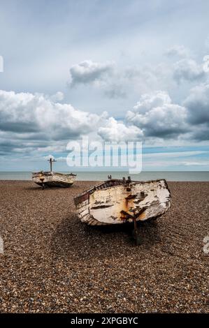 Zwei alte Fischerboote mit Holzschalen beenden ihre Tage am Aldeburgh Shingle Beach, Suffolk. Blick auf die Küste. Bewölkter Himmel. Stockfoto