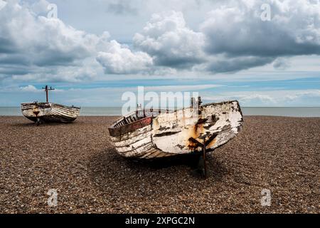 Zwei alte Fischerboote mit Holzschalen beenden ihre Tage am Aldeburgh Shingle Beach, Suffolk. Blick auf die Küste. Bewölkter Himmel. Stockfoto