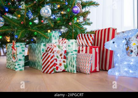 Ein wunderschön dekorierter Weihnachtsbaum mit verschiedenen Ornamenten und eingewickelten Geschenken darunter. Ein gemütliches Indoor Setting perfekt für die Weihnachtszeit, Meisterleistung Stockfoto