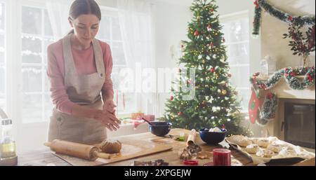 Porträt der Küchenchefin, die Teig zubereitete und Lebkuchen zu Weihnachten zuhause zubereitete. Fröhliche kleine Geschäftsinhaberin, die hausgemachtes Gebäck mit Sorgfalt für ihren Shop herstellt, bereitet sich auf den Urlaub vor Stockfoto