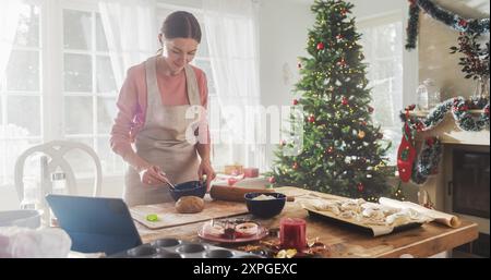 Porträt einer Frau, die Lebkuchenkekse für Weihnachten zu Hause macht. Schöne Mutter bereitet gerne Gebäck für Familie und Freunde vor, bereitet sich auf Feiertage und Abendessen vor Stockfoto