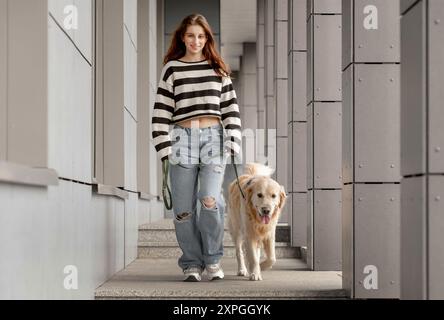 Teenager-Mädchen Spaziert Mit Golden Retriever Im Frühling In Der Stadt Stockfoto