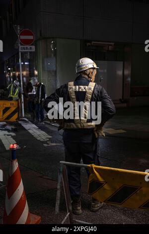 Tokio, Japan. August 2024. Japanische Bauarbeiter bauen nachts eine Straßenbaustelle auf. Neben den farbenfrohen, lebhaften und immer geschäftigen touristischen Hotspots wie Shibuya und Shinjuku bietet Tokio auch ruhigere und authentischere Gegenden, in denen Touristen lokale Küche genießen und echte Erfahrungen mit den Einheimischen machen können. Ein Beispiel für einen solchen Ort ist der alte Tsukiji Fischmarkt in der Nähe von Ginza. Quelle: SOPA Images Limited/Alamy Live News Stockfoto