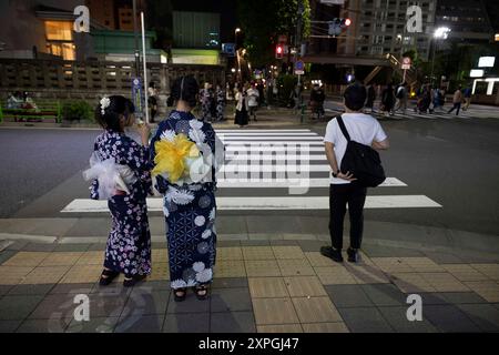 Tokio, Japan. August 2024. Mädchen in Yukata stehen an einem Fußgängerübergang. Neben den farbenfrohen, lebhaften und immer geschäftigen touristischen Hotspots wie Shibuya und Shinjuku bietet Tokio auch ruhigere und authentischere Gegenden, in denen Touristen lokale Küche genießen und echte Erfahrungen mit den Einheimischen machen können. Ein Beispiel für einen solchen Ort ist der alte Tsukiji Fischmarkt in der Nähe von Ginza. Quelle: SOPA Images Limited/Alamy Live News Stockfoto