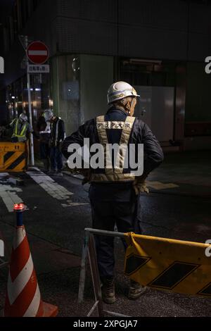 Japanische Bauarbeiter bauen nachts eine Straßenbaustelle auf. Neben den farbenfrohen, lebhaften und immer geschäftigen touristischen Hotspots wie Shibuya und Shinjuku bietet Tokio auch ruhigere und authentischere Gegenden, in denen Touristen lokale Küche genießen und echte Erfahrungen mit den Einheimischen machen können. Ein Beispiel für einen solchen Ort ist der alte Tsukiji Fischmarkt in der Nähe von Ginza. (Foto: Stanislav Kogiku / SOPA Images/SIPA USA) Stockfoto