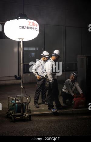Tokio, Japan. August 2024. Japanische Bauarbeiter bauen nachts eine Straßenbaustelle auf. Neben den farbenfrohen, lebhaften und immer geschäftigen touristischen Hotspots wie Shibuya und Shinjuku bietet Tokio auch ruhigere und authentischere Gegenden, in denen Touristen lokale Küche genießen und echte Erfahrungen mit den Einheimischen machen können. Ein Beispiel für einen solchen Ort ist der alte Tsukiji Fischmarkt in der Nähe von Ginza. (Credit Image: © Stanislav Kogiku/SOPA Images via ZUMA Press Wire) NUR REDAKTIONELLE VERWENDUNG! Nicht für kommerzielle ZWECKE! Stockfoto