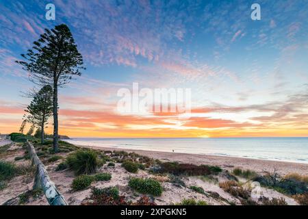 Christies Beach mit der Silhouette eines Surfers mit Surfbrett bei Sonnenuntergang, South Australia Stockfoto