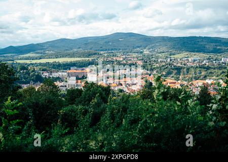 Eine charmante Stadt eingebettet zwischen grünen Hügeln und ausgedehnten Wäldern bietet zahlreiche Dächer und historische Architektur. Die Landschaft zeigt das Stockfoto