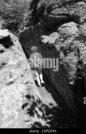 Kaukasische Frau im Alter von 50 bis 55 Jahren, die durch eine Gletscherspalte zur Rock House Cave im Petit Jean State Park in der Nähe von Morrilton, Arkansas, USA, führt Stockfoto