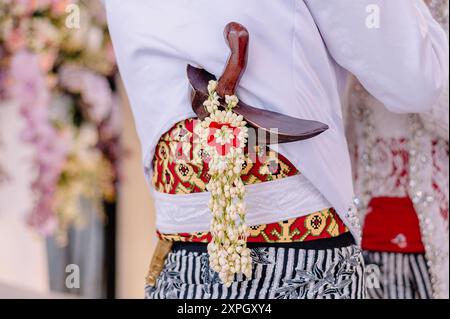 Keris, eine traditionelle indonesische Waffe, die viel Geschichte und Bedeutung hat und eine einzigartige Form hat. Versteckt im traditionellen javanischen Bräutigam-Gewand Stockfoto