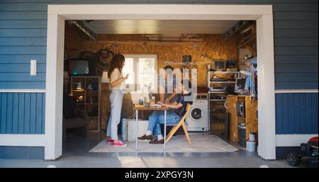 Vielfältiges Team Von Drei Gründern Der Young Startup Company, Die In Der Retro Garage Arbeiten Und Einen Alten Desktop-Computer Verwenden. Unternehmerinnen Und Unternehmer Entwickeln In Den Nostalgischen 90Er Jahren Innovativen Online-Service. Stockfoto