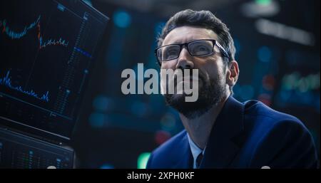 Porträt eines gutaussehenden bärtigen Börsenhändlers, der in einer Börse arbeitet. Erwachsener Mann mit Brille, erforscht Investitionsmöglichkeiten für internationale Unternehmen Stockfoto