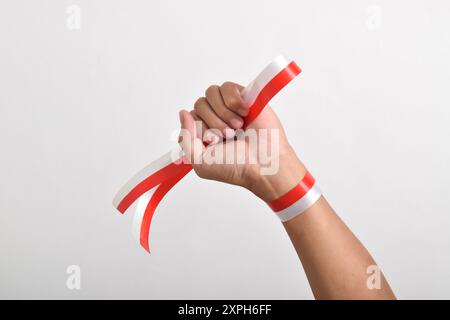 Die Hände werden mit roten und weißen Bändern als Symbol der indonesischen Flagge geballt, isoliert auf weißem Hintergrund. Indonesian Independence Day Concept, August Stockfoto